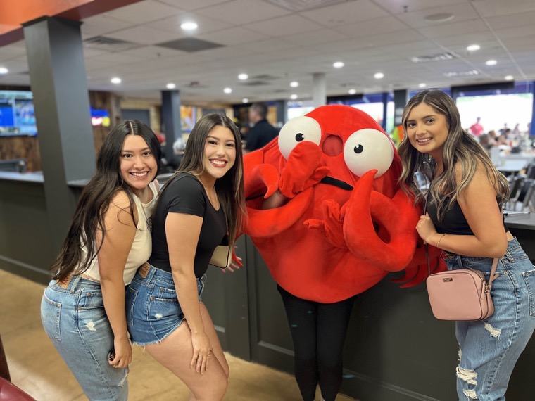 Two guests posing with the Angry Crab mascot