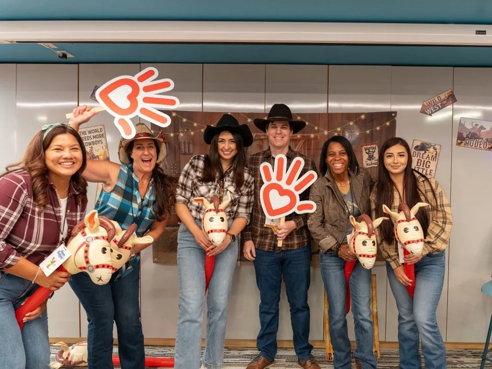 Team members in cowboy hats holding Phoenix Children’s hand signs