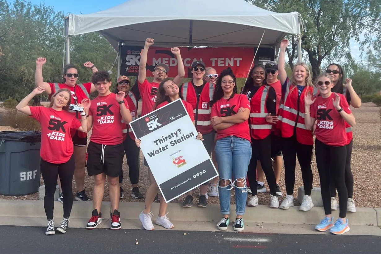 Volunteers in red 5K shirts cheering at a water station sponsored by Angry Crab Shack